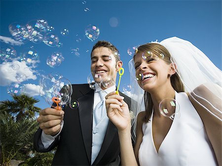 Close-up of newlywed couple blowing bubbles with a bubble wand Stock Photo - Premium Royalty-Free, Code: 640-02768125