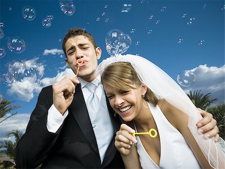 Close-up of newlywed couple blowing bubbles with a bubble wand Stock Photo - Premium Royalty-Free, Code: 640-02768126
