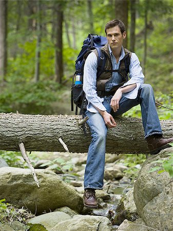 Portrait of a young man sitting on a fallen tree Stock Photo - Premium Royalty-Free, Code: 640-02768278
