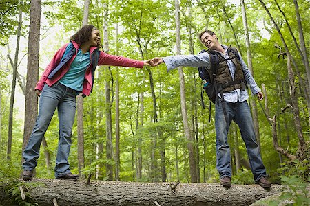 simsearch:640-02947685,k - Low angle view of a young couple holding hands and walking on a fallen tree Stock Photo - Premium Royalty-Free, Code: 640-02768286