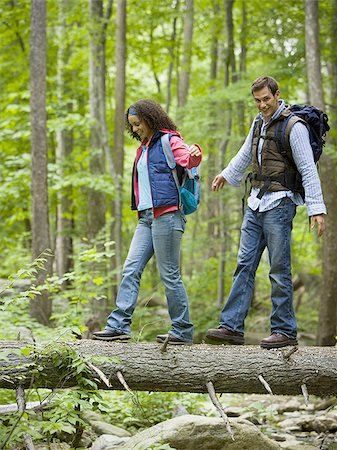Low angle view of a young couple walking on a fallen tree Stock Photo - Premium Royalty-Free, Code: 640-02768288