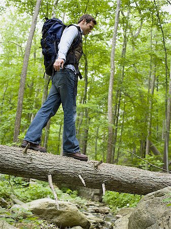 Vue d'angle faible d'un jeune homme marche sur un tronc d'arbre Photographie de stock - Premium Libres de Droits, Code: 640-02768280