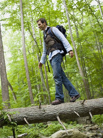 Low angle view of a young man walking on a fallen tree Stock Photo - Premium Royalty-Free, Code: 640-02768282