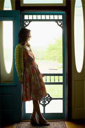 Profile of a woman leaning against a door and looking away Stock Photo - Premium Royalty-Free, Code: 640-02768311