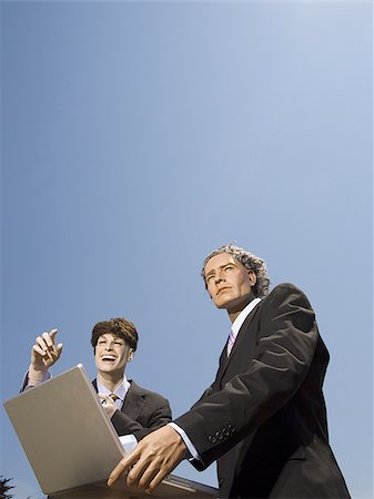 Low angle view of two mannequins portraying businessmen using a laptop Foto de stock - Sin royalties Premium, Código: 640-02768369