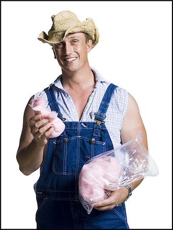 1920s-1930s Farm Boy Wearing Straw Hat And Overalls Sitting On Log