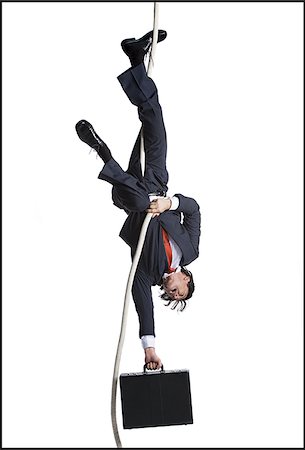 Businessman with briefcase dangling upside down from a rope Stock Photo - Premium Royalty-Free, Code: 640-02768671