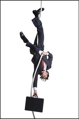 Businessman with briefcase dangling upside down from a rope Stock Photo - Premium Royalty-Free, Code: 640-02768672