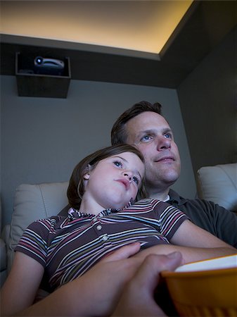 family watching tv together with popcorn - Father and daughters watching movie in home theater Stock Photo - Premium Royalty-Free, Code: 640-02769032