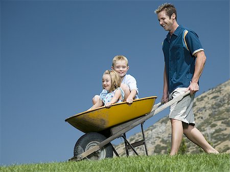 simsearch:640-02769656,k - Father pushing son and daughter in a wheelbarrow Foto de stock - Sin royalties Premium, Código: 640-02769325