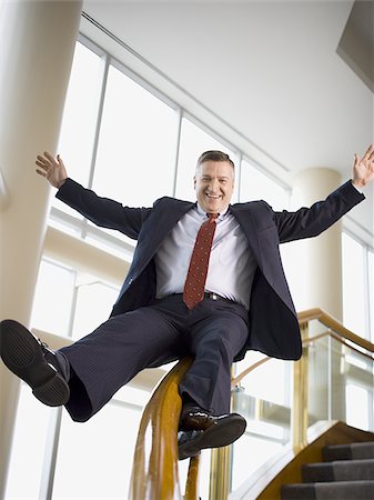 slide business man - Happy businessman sliding down stair railing Stock Photo - Premium Royalty-Free, Code: 640-02769362