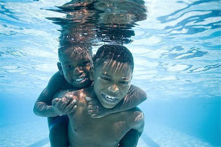 friend playing piggyback - Boys swimming underwater in pool Stock Photo - Premium Royalty-Free, Code: 640-02769503