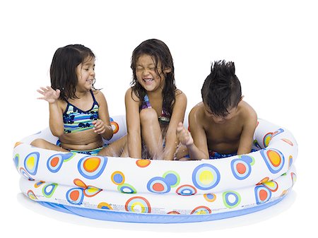 Three young children playing in inflatable pool Stock Photo - Premium Royalty-Free, Code: 640-02769655