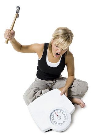 scale and frustrated - Frustrated dieting woman smashing bathroom scale with a hammer Foto de stock - Sin royalties Premium, Código: 640-02769926