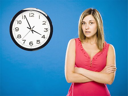 simsearch:640-01645712,k - Woman with arms crossed looking at wall clock attached to plumbing pipes Stock Photo - Premium Royalty-Free, Code: 640-02774027