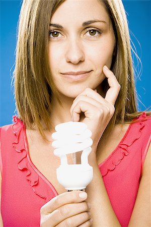 Woman holding energy efficient lightbulb smiling Stock Photo - Premium Royalty-Free, Code: 640-02774034