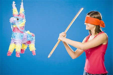 Woman with blindfold hitting pinata with stick Stock Photo - Premium Royalty-Free, Code: 640-02774038