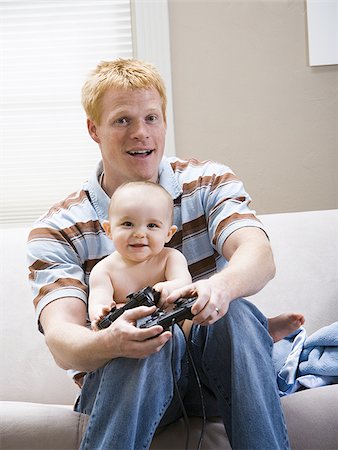 sofa two boys video game - Man and baby on sofa with video game controller smiling Stock Photo - Premium Royalty-Free, Code: 640-02774078