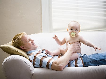 Man lying down on sofa with baby Stock Photo - Premium Royalty-Free, Code: 640-02774098