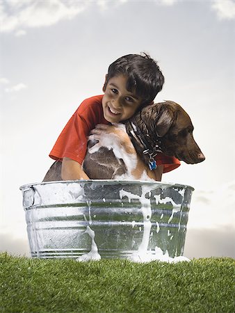 Smiling boy hugging and bathing dog outdoors on cloudy day Stock Photo - Premium Royalty-Free, Code: 640-02774342
