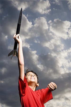 fusée - Garçon jouant avec fusée jouet à l'extérieur sur la journée nuageuse faible angle vue Photographie de stock - Premium Libres de Droits, Code: 640-02774359