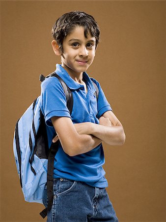 Boy standing with arms crossed and backpack smiling Stock Photo - Premium Royalty-Free, Code: 640-02774373