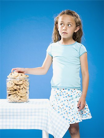Girl sneaking Chocolate Chip Cookie from cookie jar Foto de stock - Sin royalties Premium, Código: 640-02774390