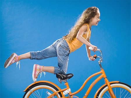 simsearch:640-03261020,k - Fille sur vélo orange à genoux sur le siège avec le pied vers le haut Photographie de stock - Premium Libres de Droits, Code: 640-02774429