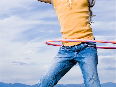 Mid section view of girl with hula hoop outdoors with clouds Stock Photo - Premium Royalty-Free, Code: 640-02774434