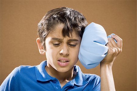 Boy holding ice pack to head Fotografie stock - Premium Royalty-Free, Codice: 640-02774630