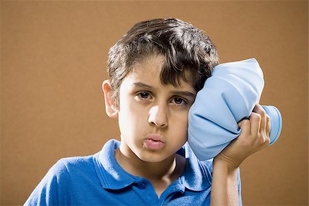 Boy holding ice pack to head Stock Photo - Premium Royalty-Free, Code: 640-02774633