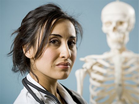 photograph woman and skeleton - Female doctor smiling with skeleton in background Stock Photo - Premium Royalty-Free, Code: 640-02774820