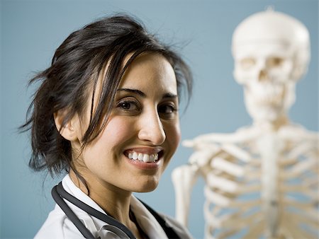skeletons human not illustration not xray - Female doctor smiling with skeleton in background Stock Photo - Premium Royalty-Free, Code: 640-02774821
