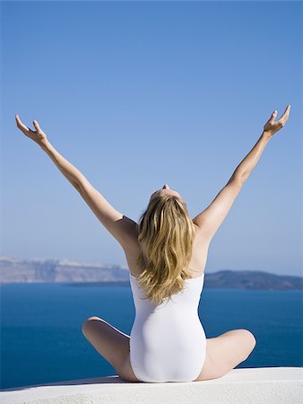 Rear view of woman in swimsuit with arms up Stock Photo - Premium Royalty-Free, Code: 640-02774919