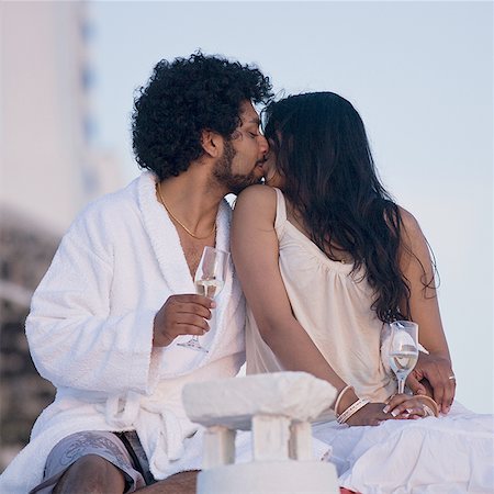 Couple sitting outdoors with champagne flutes and scenic background smiling and snuggling Stock Photo - Premium Royalty-Free, Code: 640-02775022