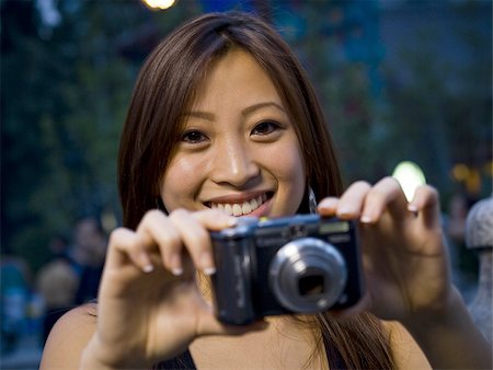 simsearch:640-01601405,k - Woman taking a photograph smiling Foto de stock - Royalty Free Premium, Número: 640-02775069