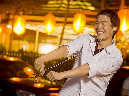 Man with mp3 player dancing and smiling outdoors Stock Photo - Premium Royalty-Free, Code: 640-02775075