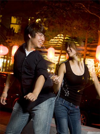 Couple listening to mp3 player outdoors dancing and smiling Stock Photo - Premium Royalty-Free, Code: 640-02775079