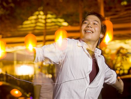 people dancing in night club with arms in air - Man with mp3 player dancing and smiling outdoors Stock Photo - Premium Royalty-Free, Code: 640-02775073