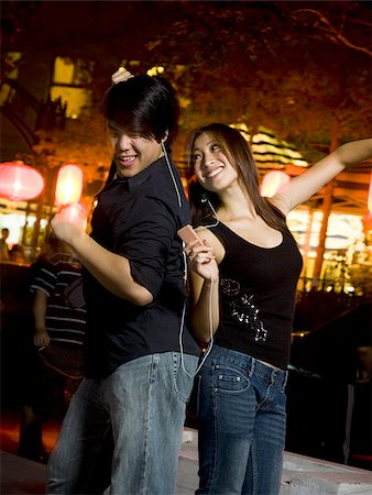 Couple listening to mp3 player outdoors dancing and smiling Stock Photo - Premium Royalty-Free, Code: 640-02775082