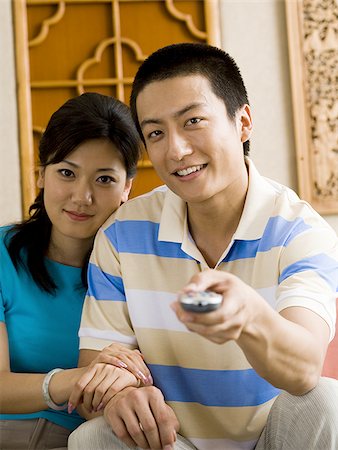 simsearch:640-02772458,k - Couple sitting on sofa watching television smiling Stock Photo - Premium Royalty-Free, Code: 640-02775119