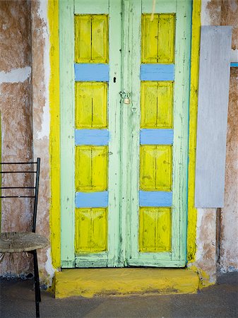 Door painted yellow blue and green with window and empty chair Stock Photo - Premium Royalty-Free, Code: 640-02775169