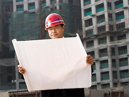 Construction site foreman with blueprints outdoors Stock Photo - Premium Royalty-Free, Code: 640-02775505