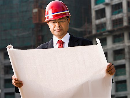 Construction site foreman with blueprints outdoors Stock Photo - Premium Royalty-Free, Code: 640-02775507