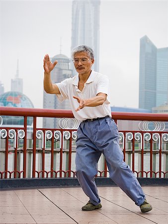 Man doing tai chi outdoors with city skyline in background Stock Photo - Premium Royalty-Free, Code: 640-02775572