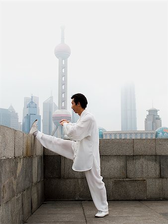 Man doing tai chi outdoors with city skyline in background Stock Photo - Premium Royalty-Free, Code: 640-02775573