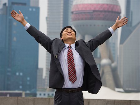 Businessman with arms up and city skyline in background Stock Photo - Premium Royalty-Free, Code: 640-02775596