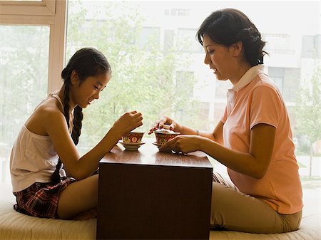 Profile of woman and girl sitting cross legged in front of large window Stock Photo - Premium Royalty-Free, Code: 640-02775632