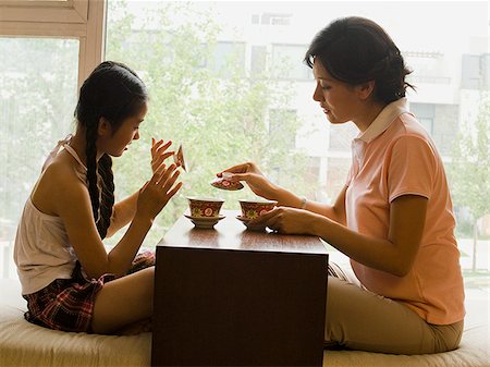 Profile of woman and girl sitting cross legged in front of large window Stock Photo - Premium Royalty-Free, Code: 640-02775633