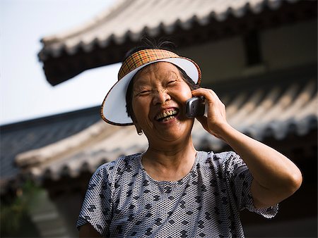 simsearch:640-01601405,k - Woman with sun visor outdoors smiling talking on cell phone Foto de stock - Royalty Free Premium, Número: 640-02775714